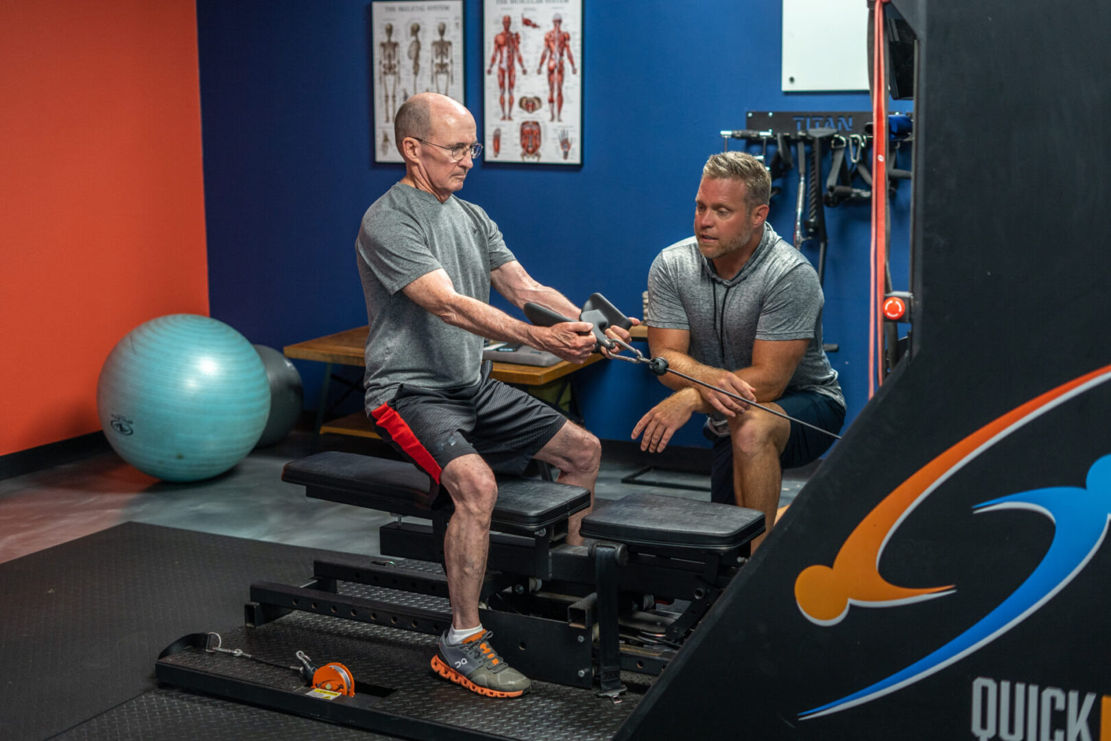 A trainer training a senior man with weights